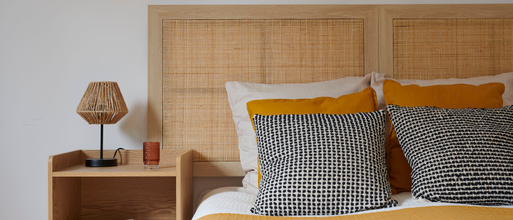 Détail d'une prestation de home staging dans une chambre avec lit coussins lampe table